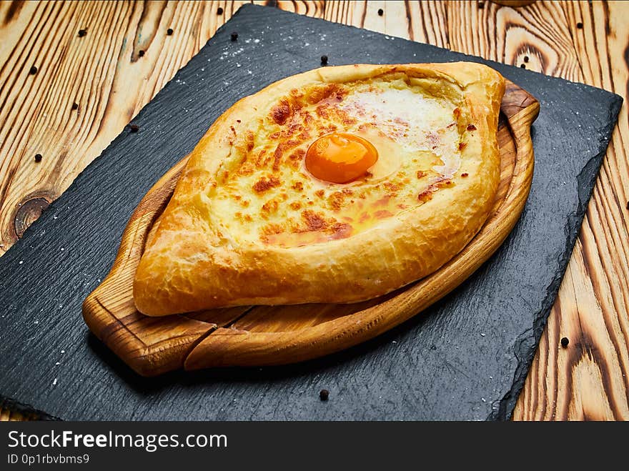 Ajarian Khachapuri traditional Georgian cheese pastry with eggs on cutting board . Homemade baking. Open pie with mozzarella