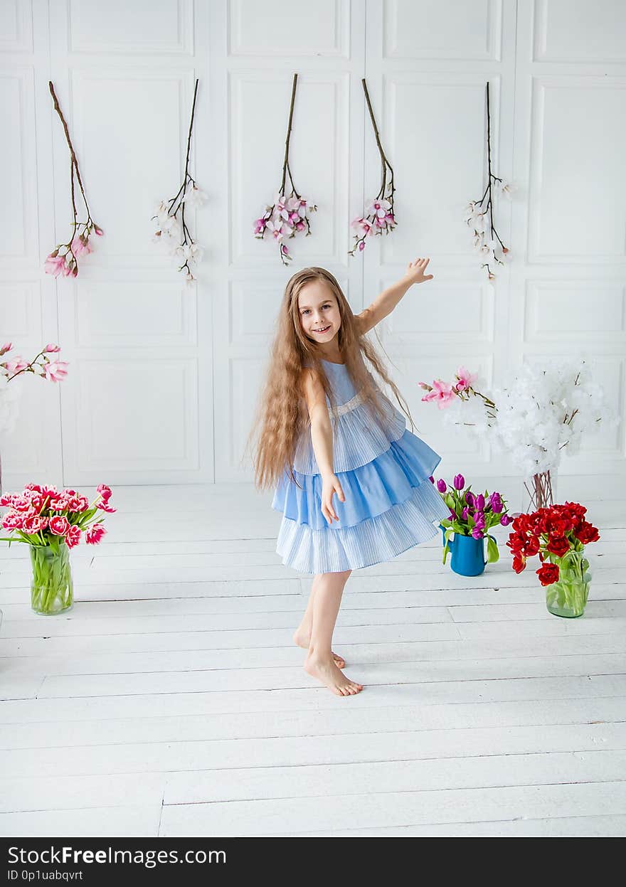 Portrait of a beautiful blue-eyed girl, a little girl among spring flowers in a bright room. Spring break, Mother`s Day, Women`s Day, Easter