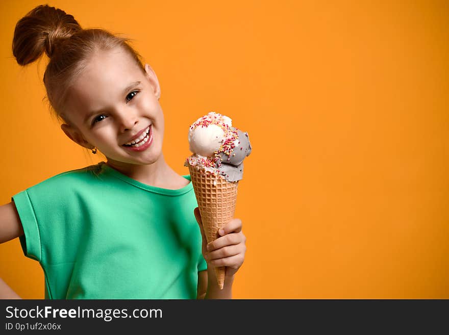 Little baby girl kid eating vanilla ice cream in waffles cone on yellow background. Banner