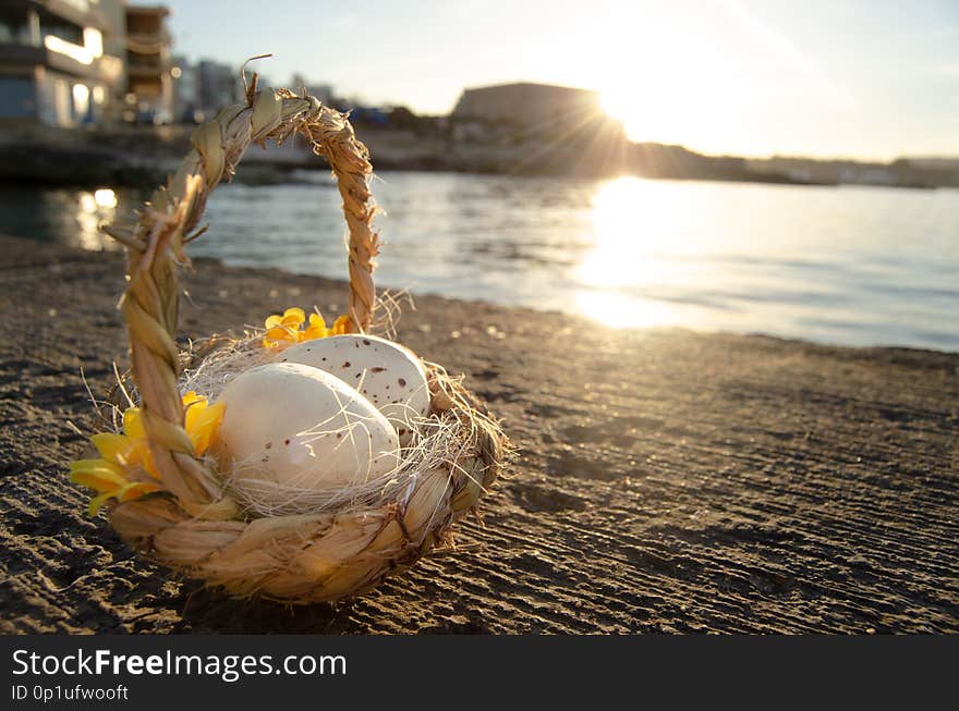 Small basket with two easter eggs on the sea doc on golden hour easter concept