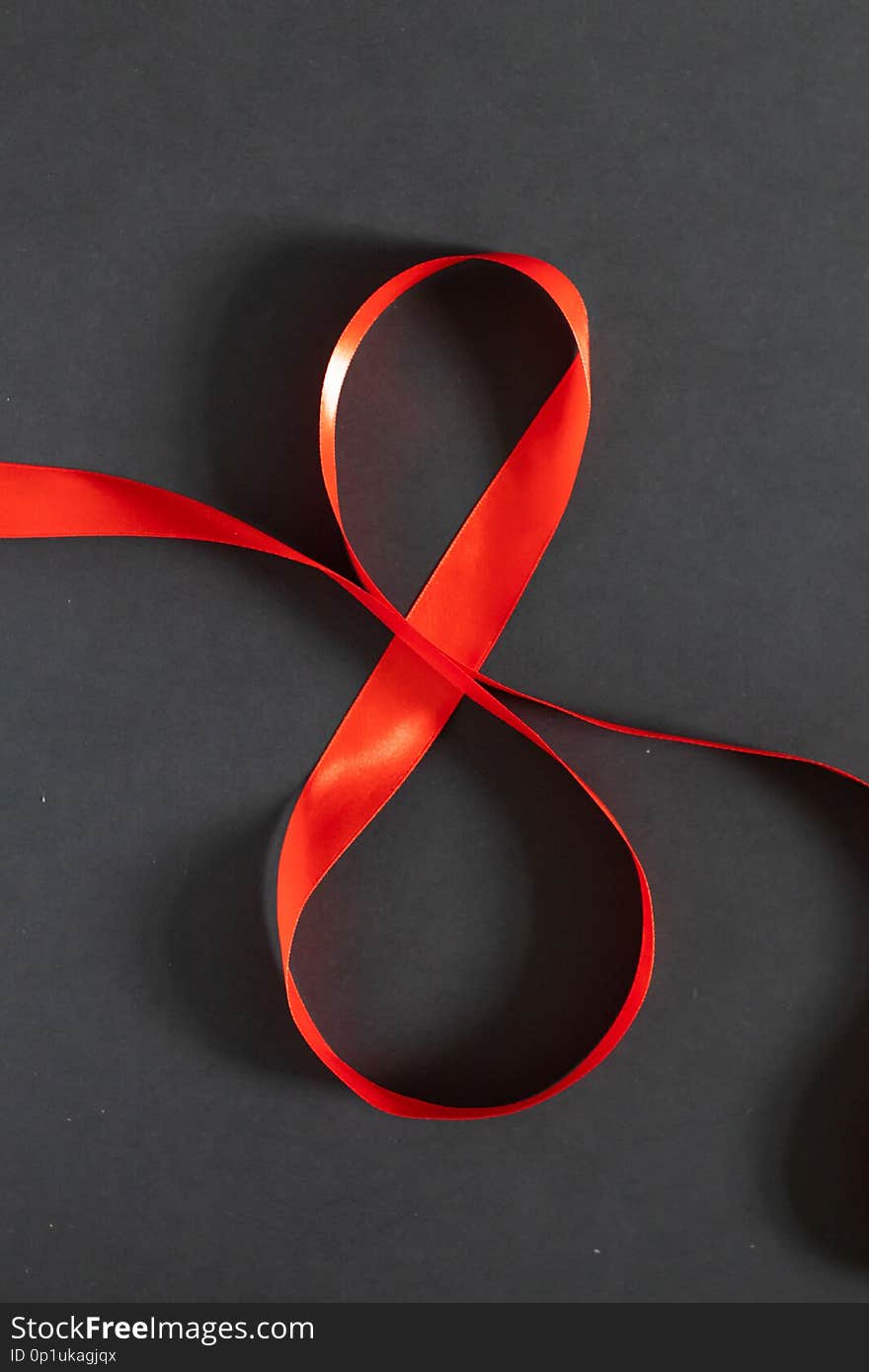 8 March Women`s day background. Red ribbon eight on a black board.