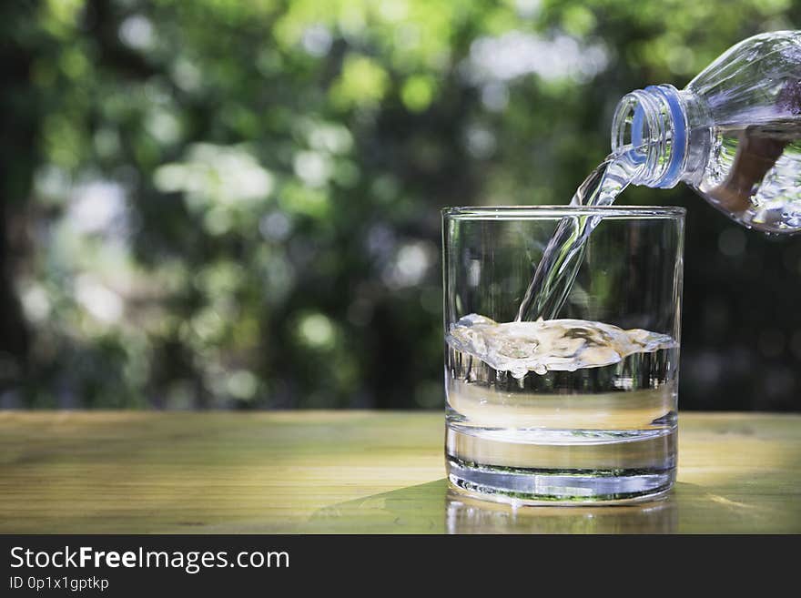 Hand holding water bottle on wooden in nature background.