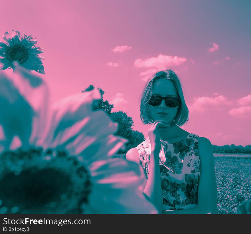 Duotone portrait of young woman in sunglasses and floral dress staing in the field