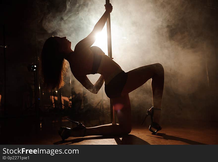 Pole dancing. An attractive woman pole dancer performing.