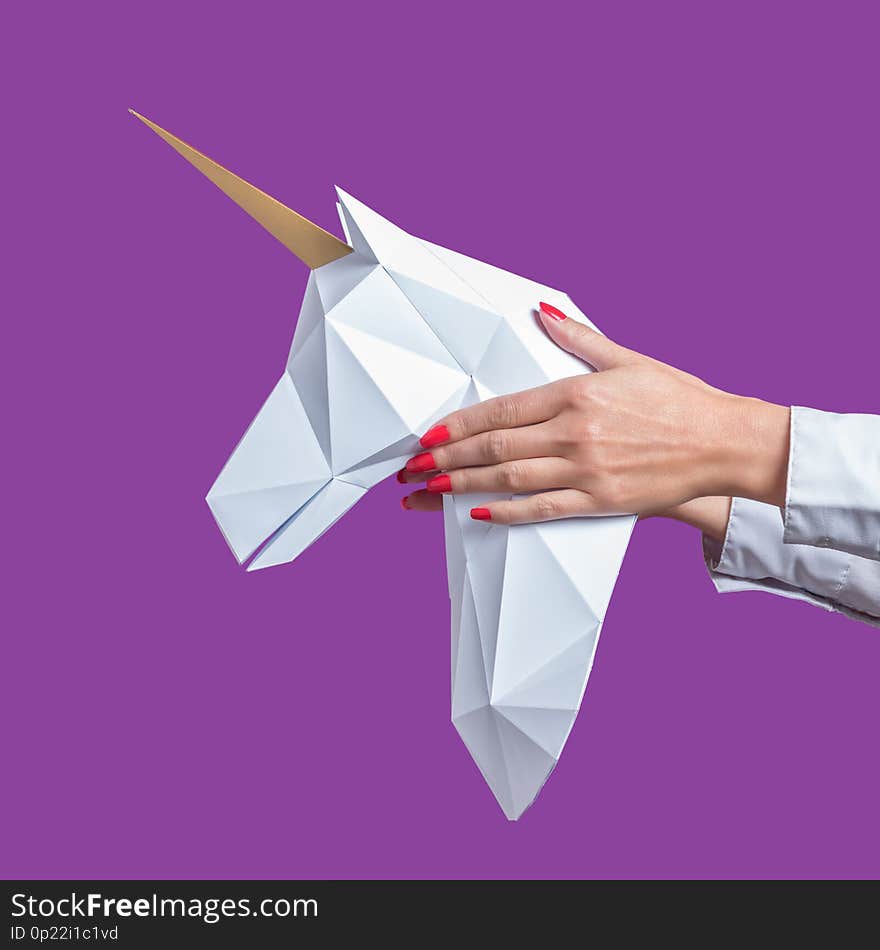 Hands hold a white 3d papercraft model of Unicorn. Minimal Art concept