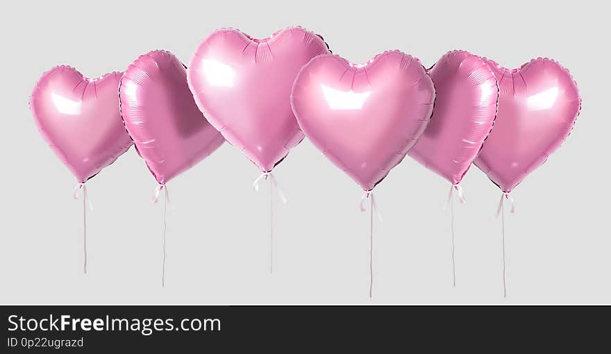 Bunch of pink color heart shaped foil balloons isolated on bright background. Minimal love concept