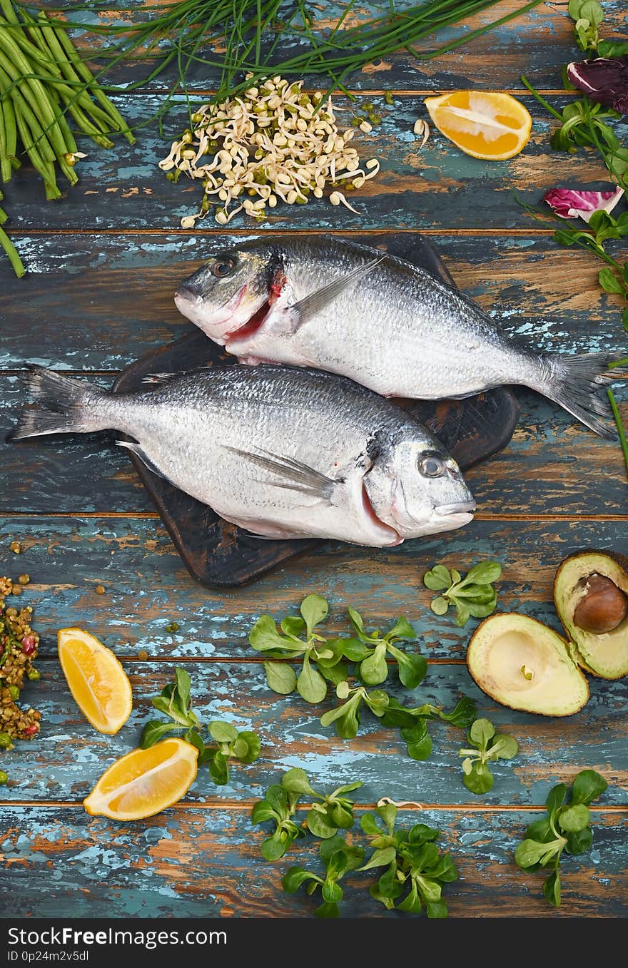 Dorado and natural ingredients for healthy food on rough dyed wooden background.