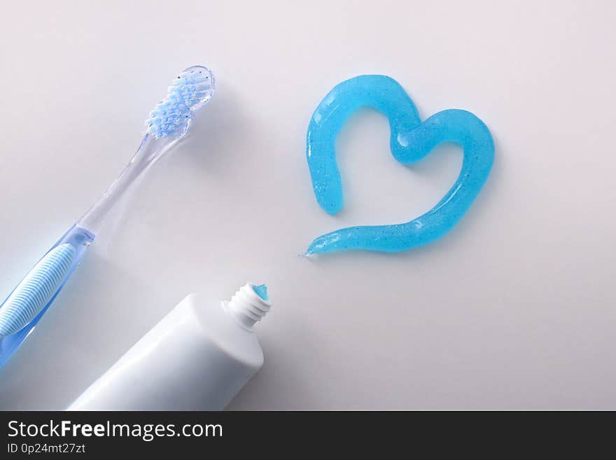 Dental health concept with toothbrush tube and toothpaste heart on white table detail. Horizontal composition. Top view. Dental health concept with toothbrush tube and toothpaste heart on white table detail. Horizontal composition. Top view