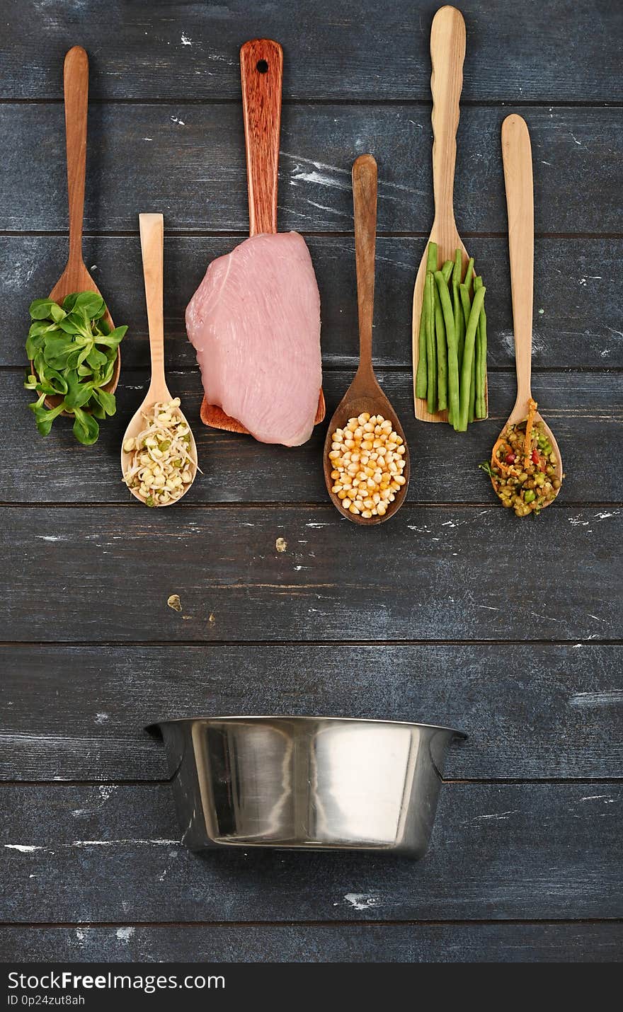 Set of various ingredients in wooden spoons for pet food. Lined in the form of geometric shapes on rough dyed wooden background. Flat lay.