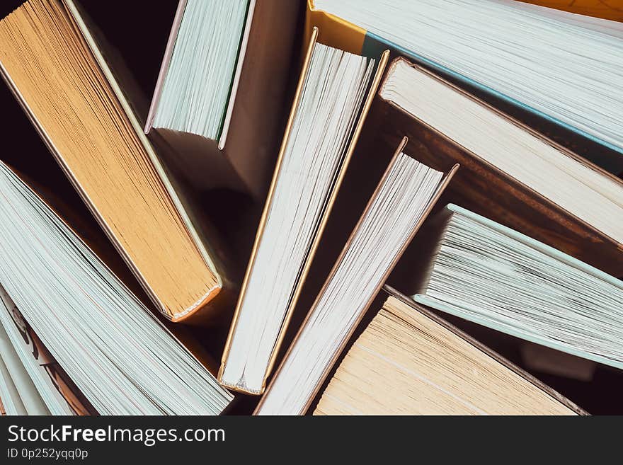 A stack of thick open books stand on a dark background. Back to school. Education background. A stack of thick open books stand on a dark background. Back to school. Education background