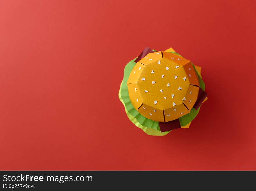 Paper cheeseburger with beef, cheese, tomato, lettuce, onion, bacon and sauce on red background. Copy space. Creative or art food