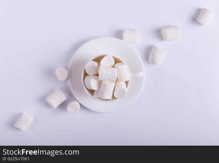 Empty ceramic cup with marshmallows on a saucer, on a white background. Hard shadow from the sun, the concept of morning