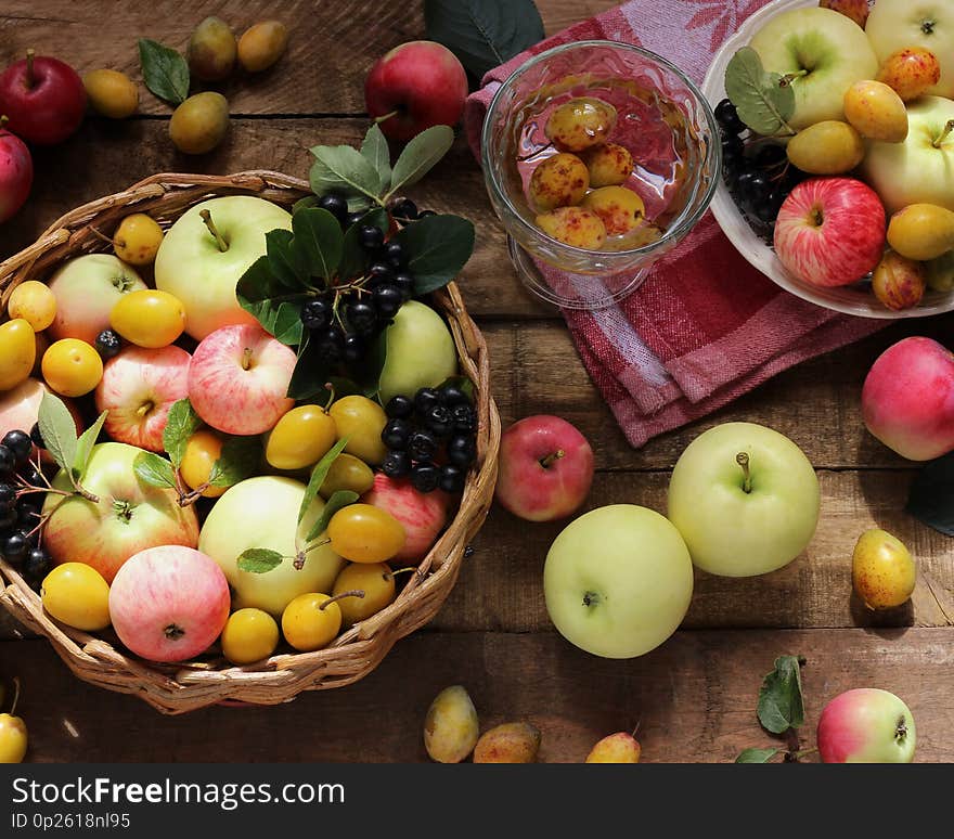 Village garden berries and fruits: apples of different varieties, plums, Rowan in the basket. Food on a rough wooden table, top view. Village garden berries and fruits: apples of different varieties, plums, Rowan in the basket. Food on a rough wooden table, top view