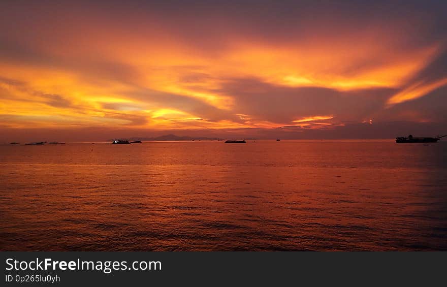 Orange sky during sunset in summer. Many boats& x27; floating on the calm sea.