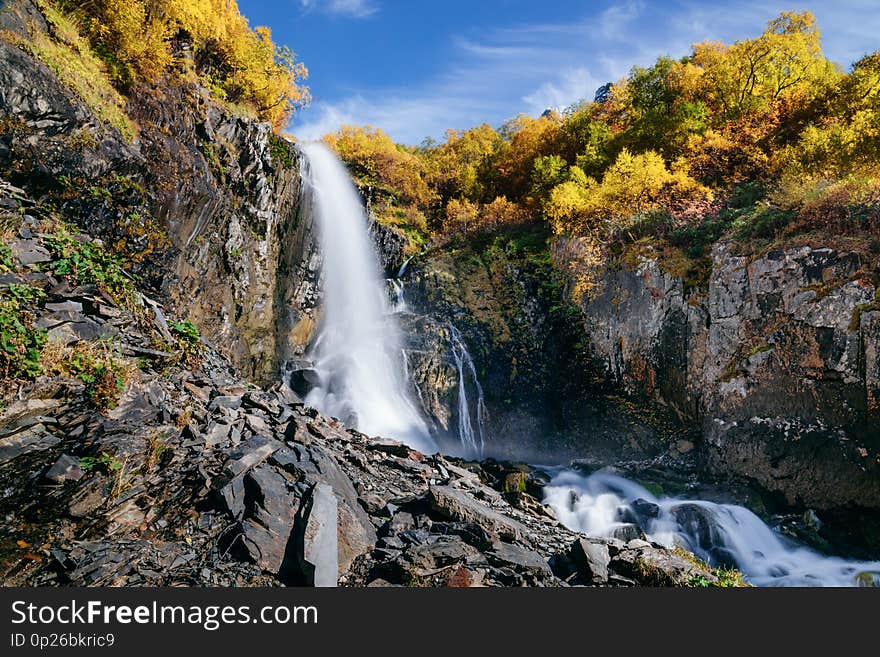 High waterfall in the mountains in the fall. Chuchhursky waterfall, Dombay, Caucasus