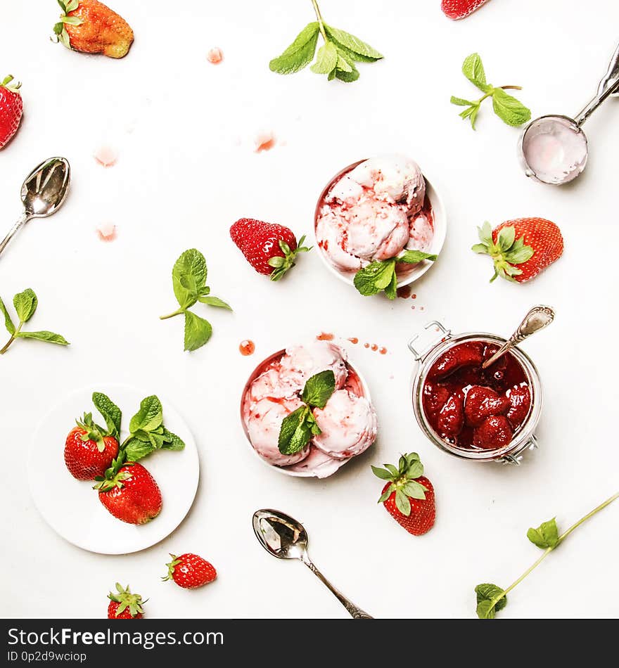 Strawberry ice cream with jam topping, decorated with green mint leaves, gray kitchen table background, top view. Strawberry ice cream with jam topping, decorated with green mint leaves, gray kitchen table background, top view