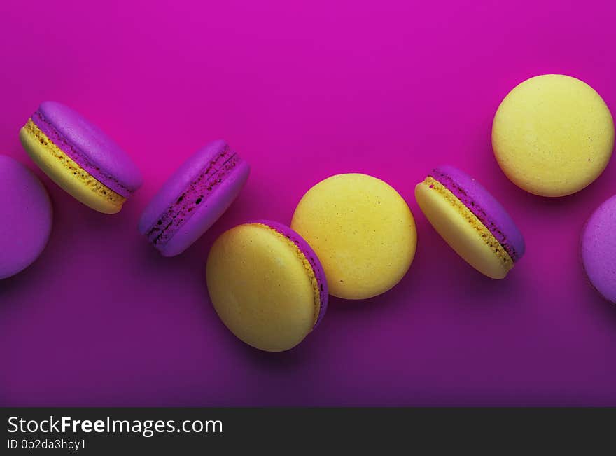 Pink yellow macaroons on soft pink background table, place for text, minimalism style, violet purple neon color, top view