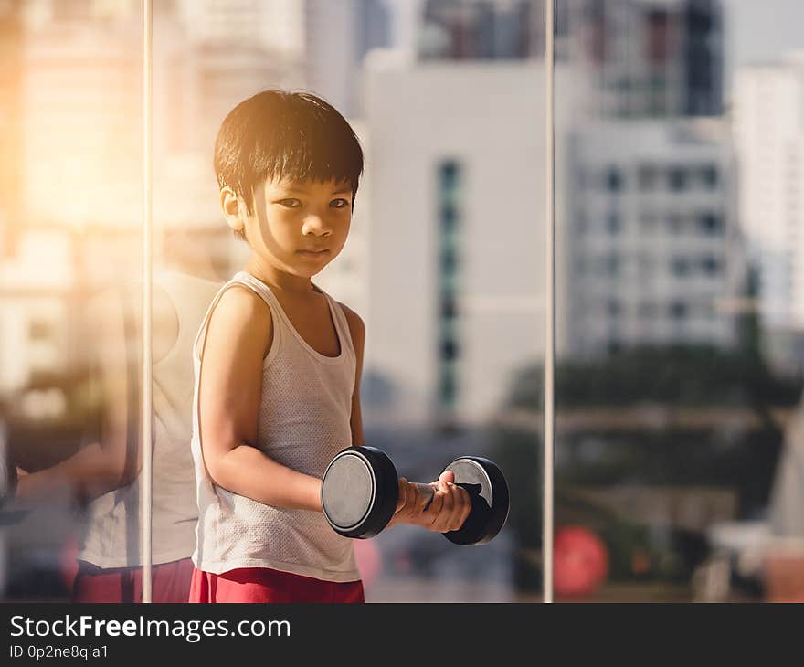 Boy is working out with dumbbell by the windows city