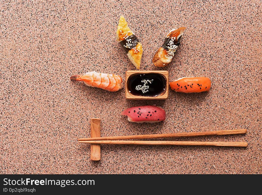 Assorted sushi set on a brown stone background. Japanese food sushi, soy sauce, chopsticks. Top view, copy space