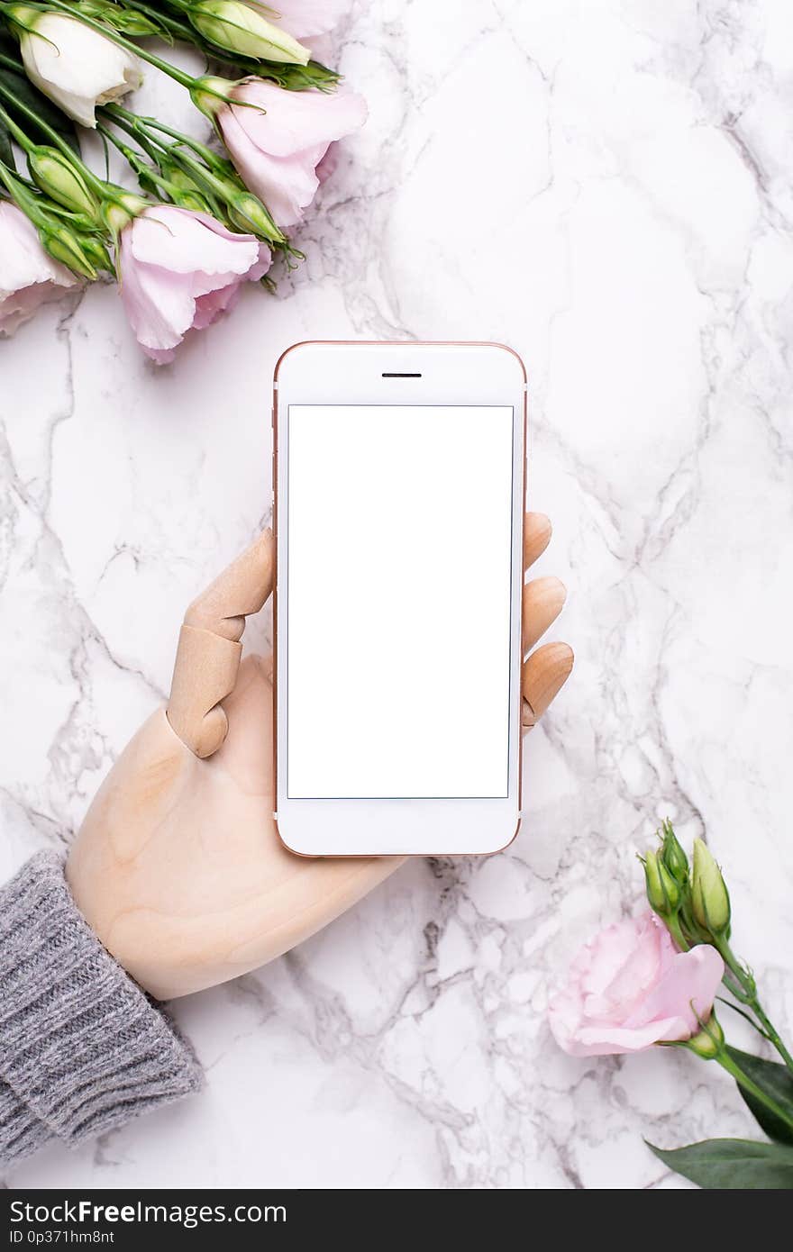 Wooden Hand With Mobile Phone On Marble Office Background With Pink Flowers