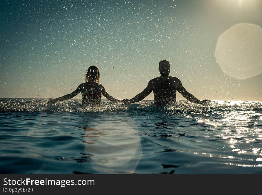 Happy couple playing in the sea. Man and women having fun on summer vacation. Healthy active lifestyle concept. Happy couple playing in the sea. Man and women having fun on summer vacation. Healthy active lifestyle concept