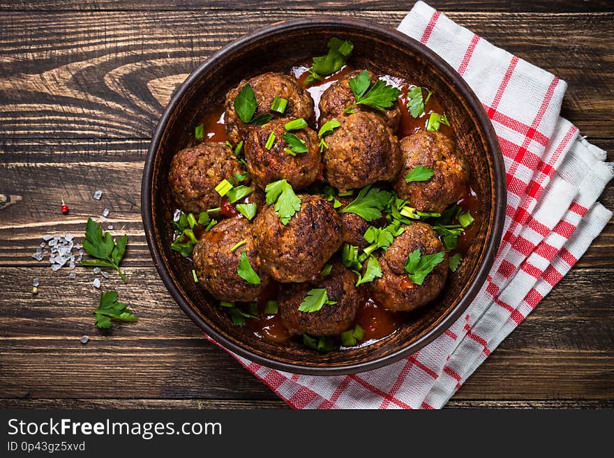 Meatballs in tomato sauce on wooden table top view.