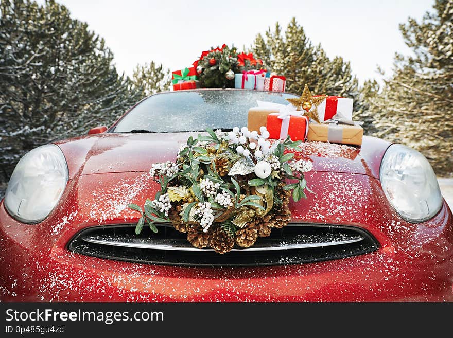 Car with Christmas wreath, tree and gifts in winter forest, closeup