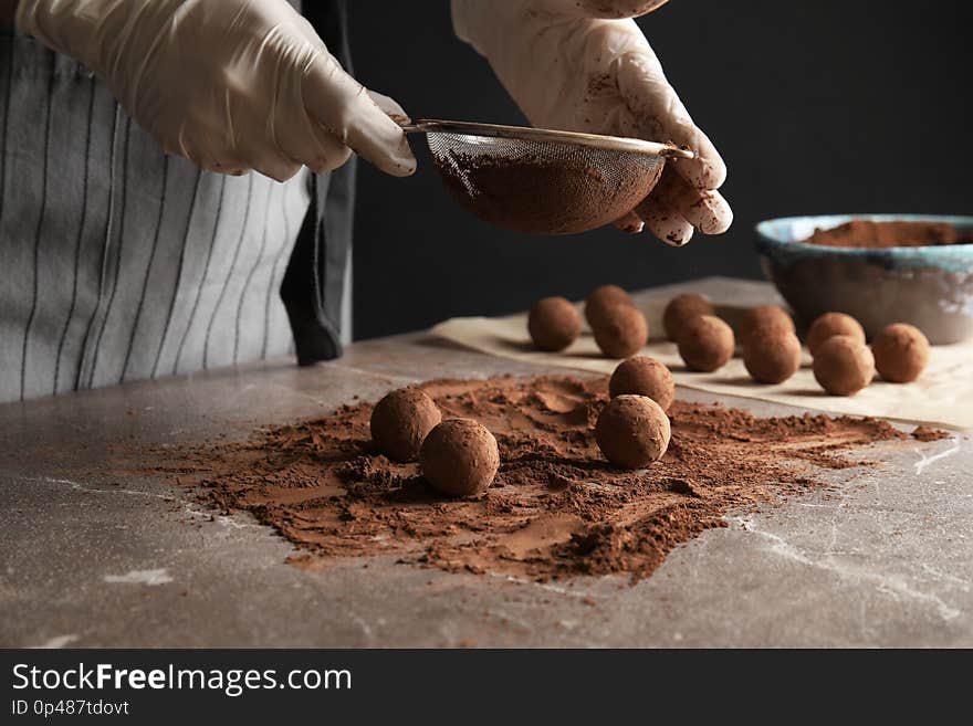 Woman preparing tasty chocolate truffles at table