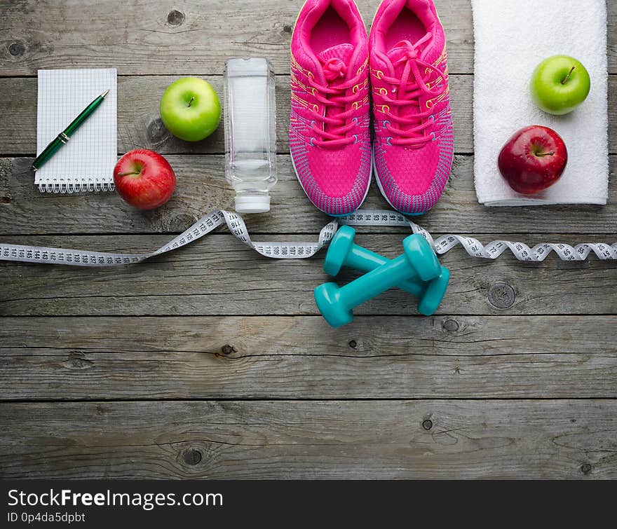 Sneakers Dumbbells Bottle Of Water And Apple On Wooden Table