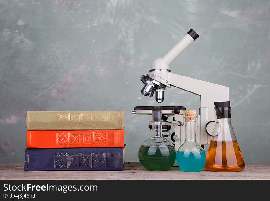 Education and science concept - books and microscope on the table on grey background