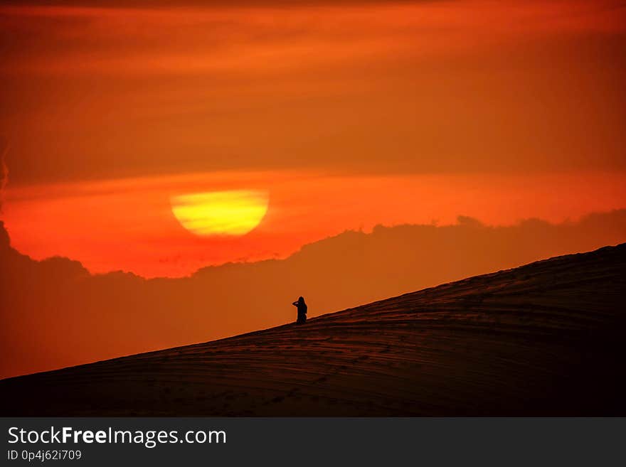 Woman sitting in the sand and watching the sun go down. Woman sitting in the sand and watching the sun go down