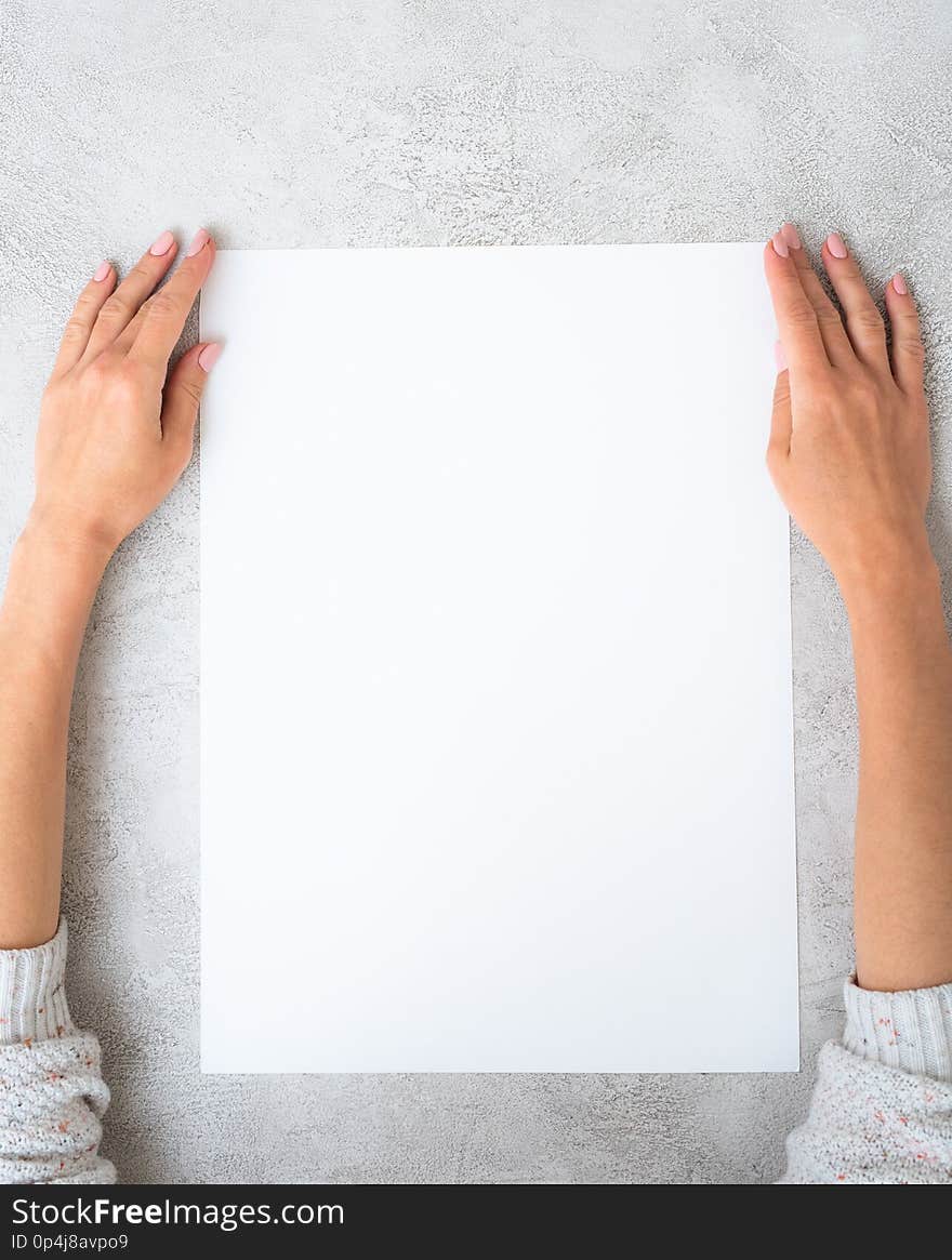 Girl`s hands holding a big white sheet of paper. Girl`s hands holding a big white sheet of paper