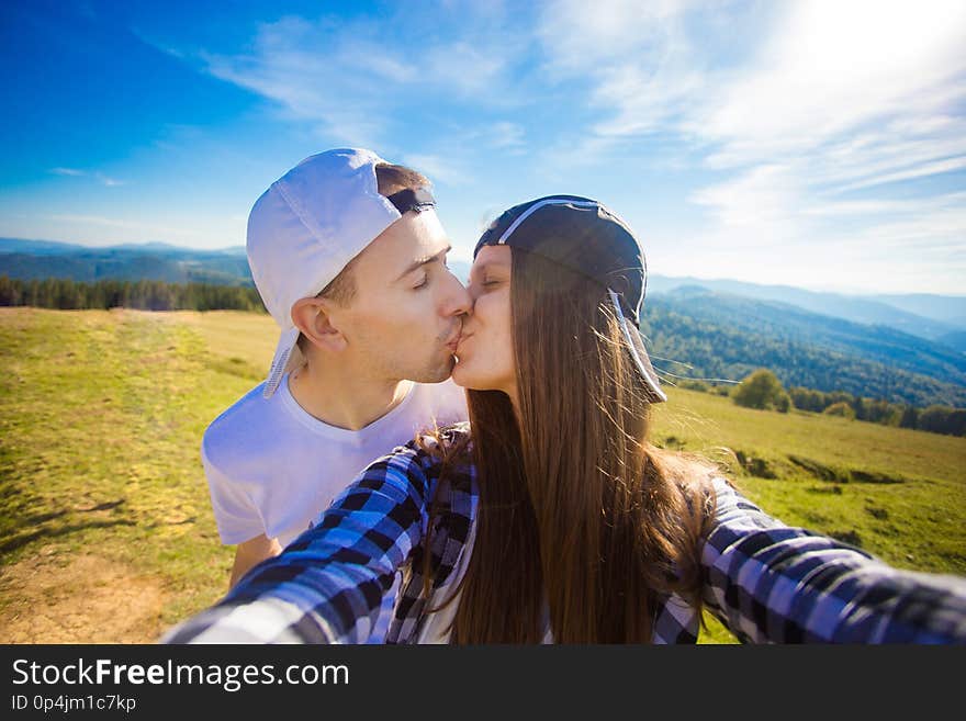 Young couple hiking taking selfie with smart phone. Happy young man and woman taking self portrait with mountain scenery backgrou