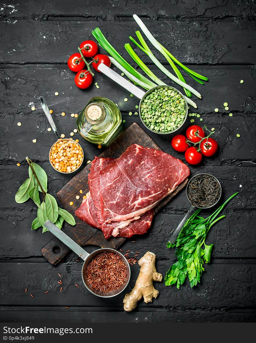 Healthy food. Raw beef steaks with organic vegetables and spices . On a black rustic background