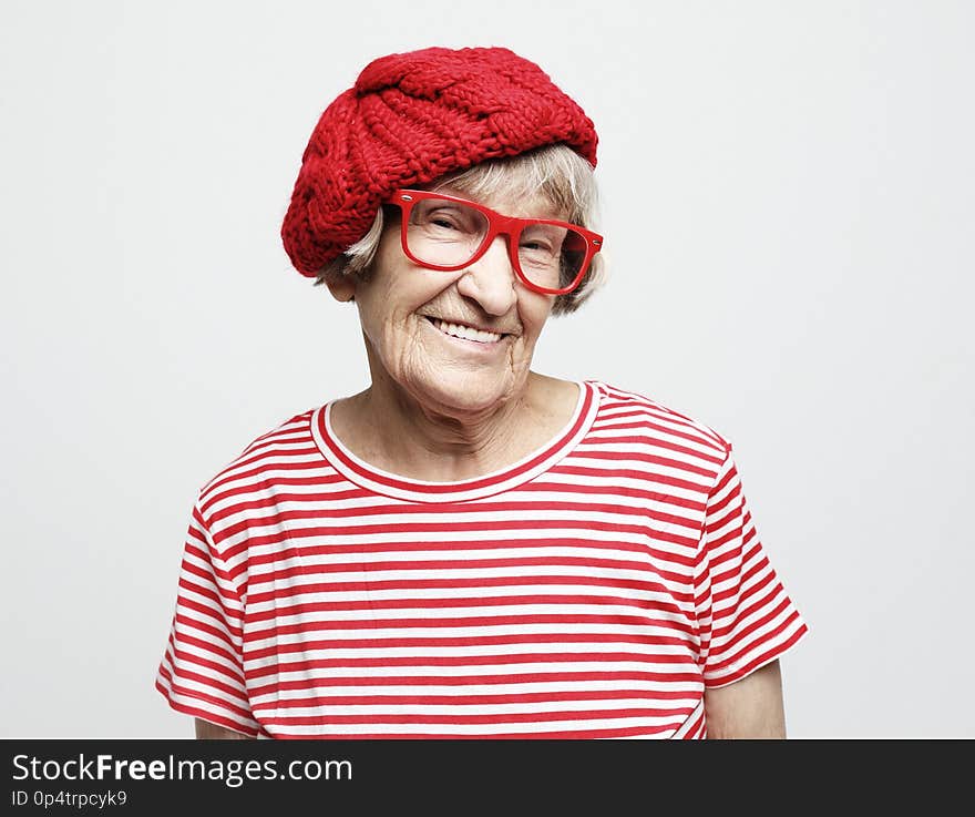 Grey haired old nice beautiful woman wearing red hat and glasses. Isolated over vwhite background