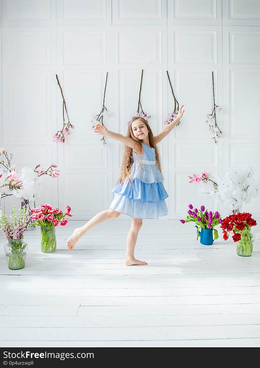 Portrait of a beautiful blue-eyed girl, a little girl among spring flowers in a bright room. Spring break, Mother`s Day, Women`s Day, Easter