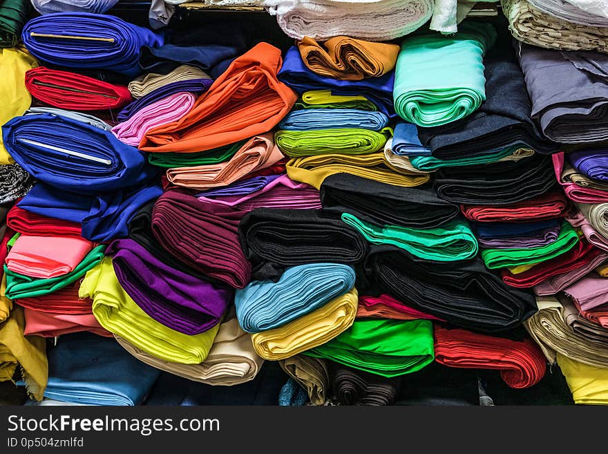 Fabric store. Warehouse with stacked colored rolls of fabrics for sewing.