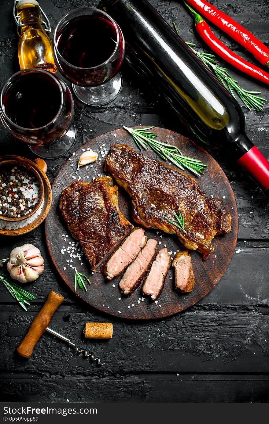 Grilled beef steaks with herbs and red wine. On a black rustic background