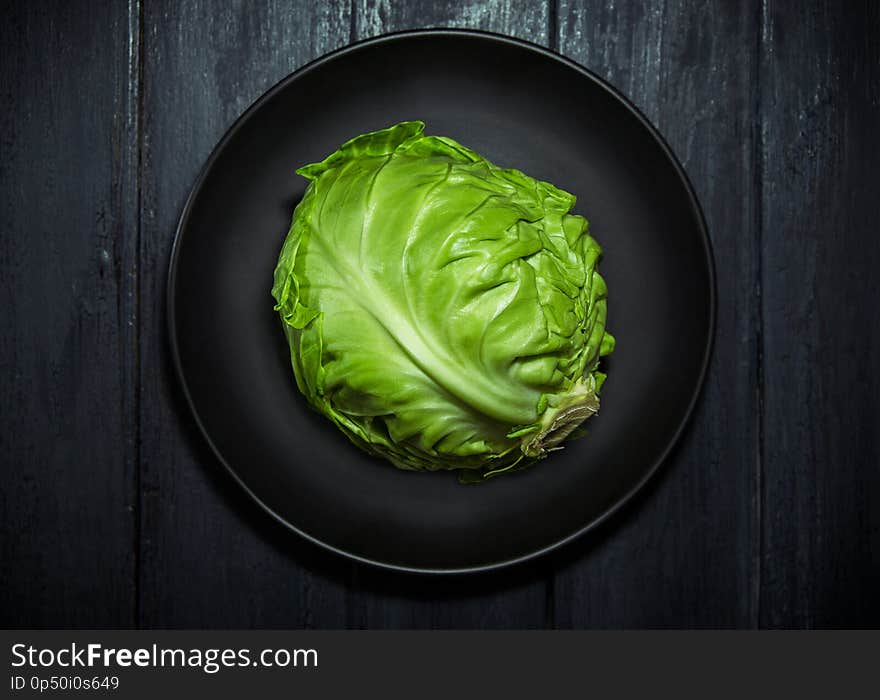 Fresh green cabbage in a black plate on wooden background. Fresh green cabbage in a black plate on wooden background