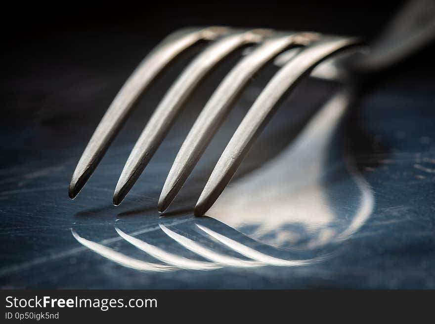 Close-up vintage fork on reflective metal background