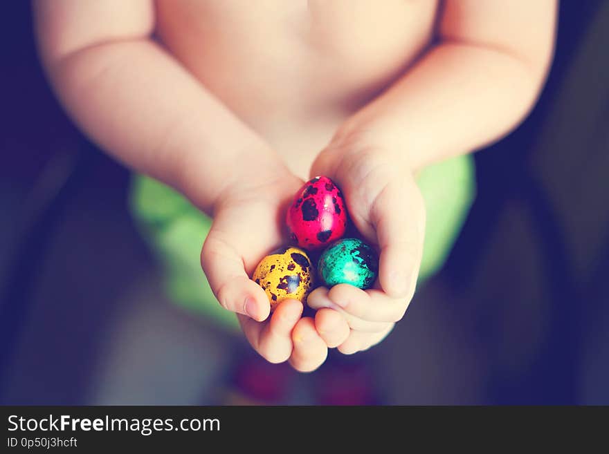 Colorful easter eggs in child hands after egg-hunt.