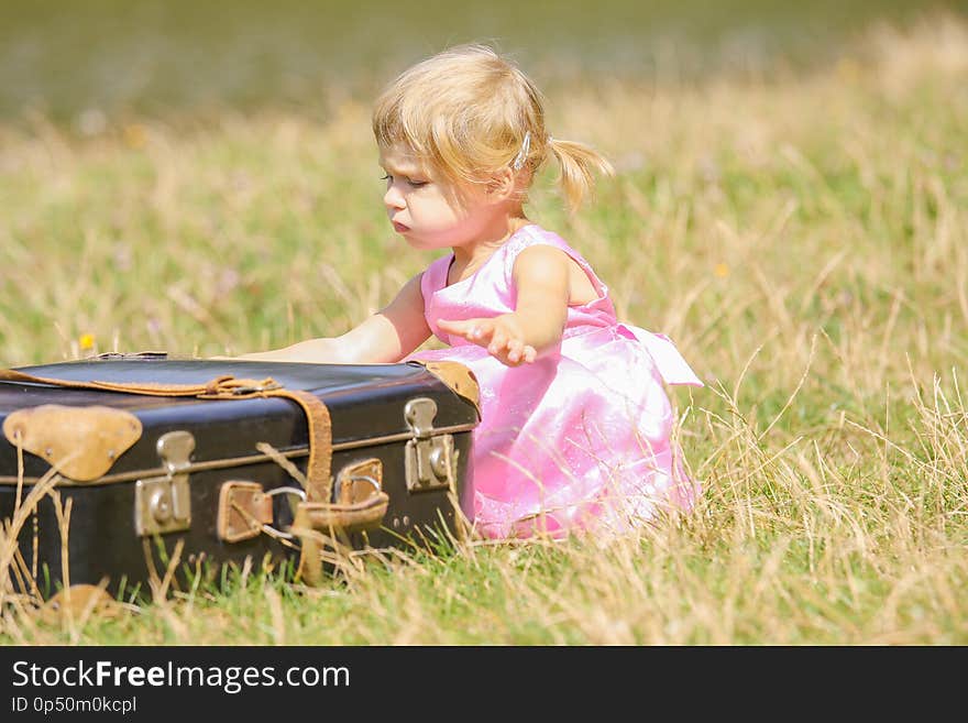 Happy girl with a suitcase outdoors at the park