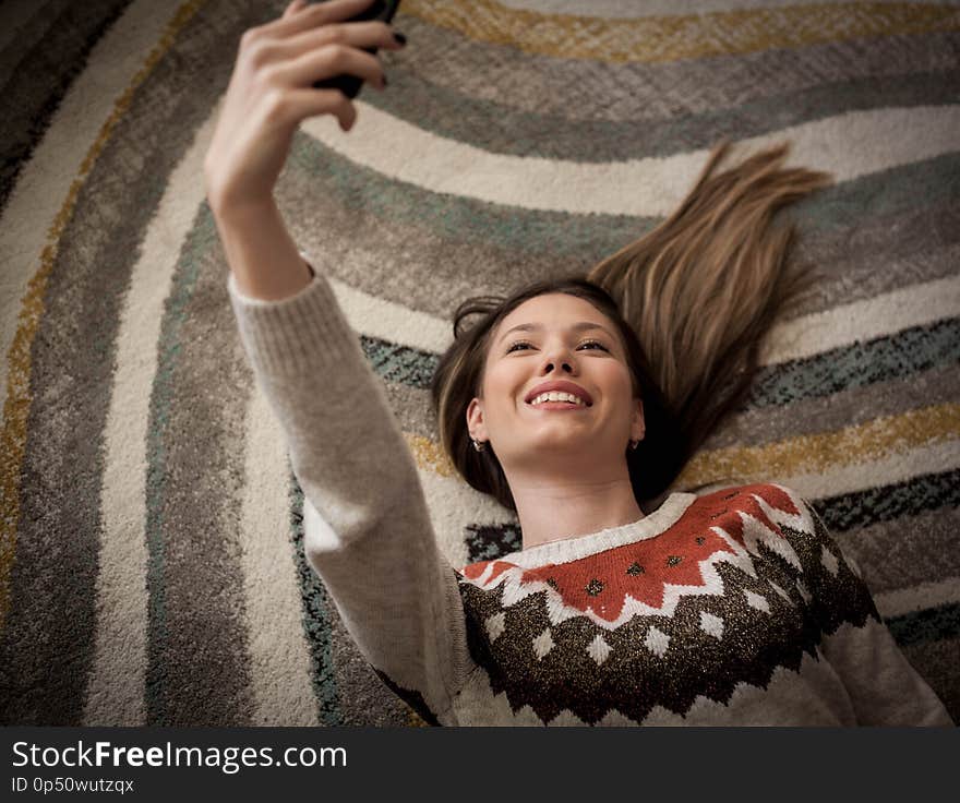 Woman taking a sefie on the floor. Woman taking a sefie on the floor