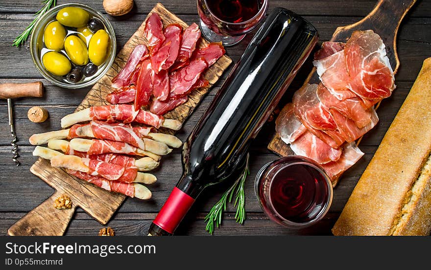 Antipasto background.Various meat appetizer with olives, jamon and red wine. On a wooden background