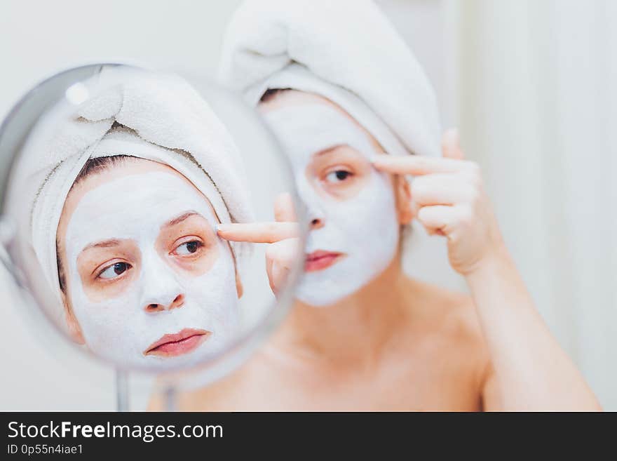 Young woman putting a mask on her face in the bathroom