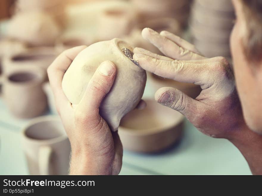 Male potter making ceramic cup, pottery studio background