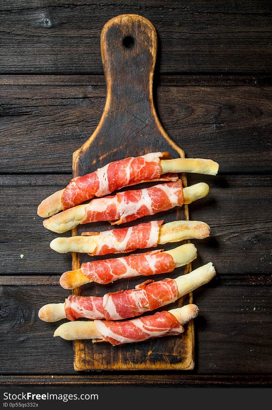Meat appetizer on bread sticks. On a wooden background