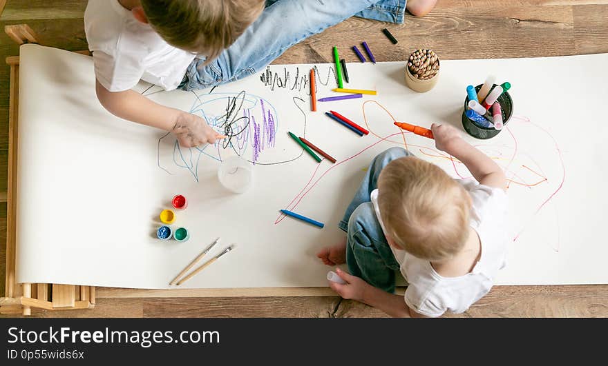 Kids painting with different materials on large canva on the flour