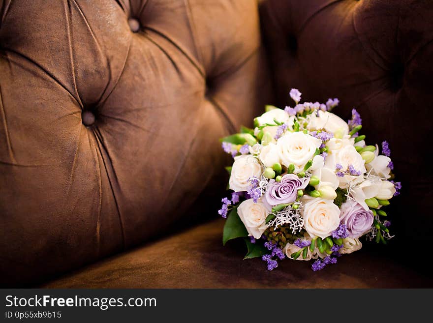 Bouquet in brown sofa. Purple and creamy roses in still life concept. Bouquet in brown sofa. Purple and creamy roses in still life concept