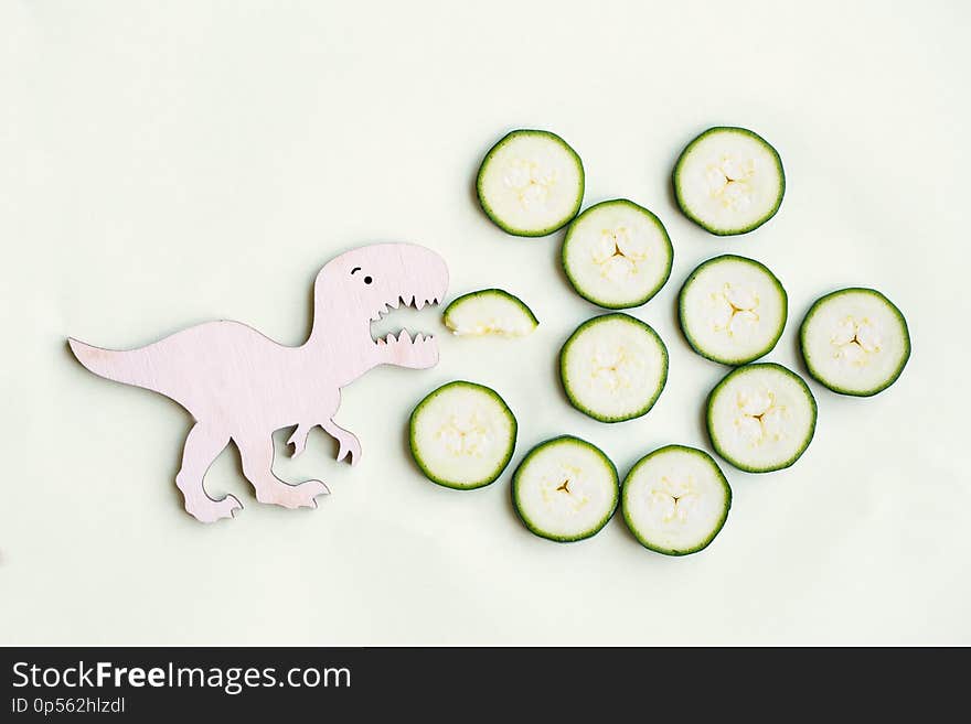 Funny strong dinosaur eating tasty zucchini, healthy vegetables for children, funny meal, flat lay